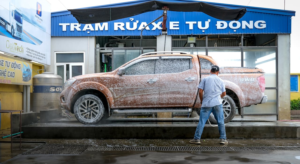 The Art of Drawing Readers In: Your attractive post title goes here A pickup truck being cleaned at a modern automated car wash facility with a worker present.